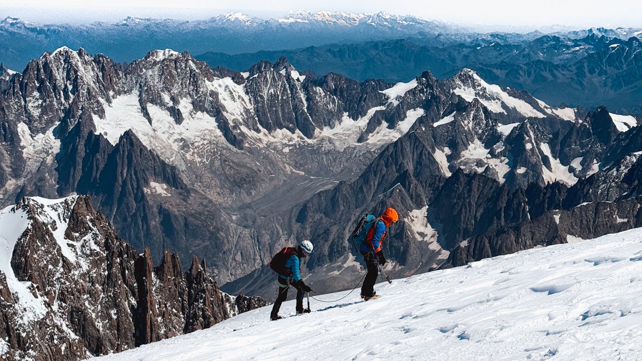 Two climbers scale the snowy slopes of Chamonix, France, amidst stunning alpine vistas.